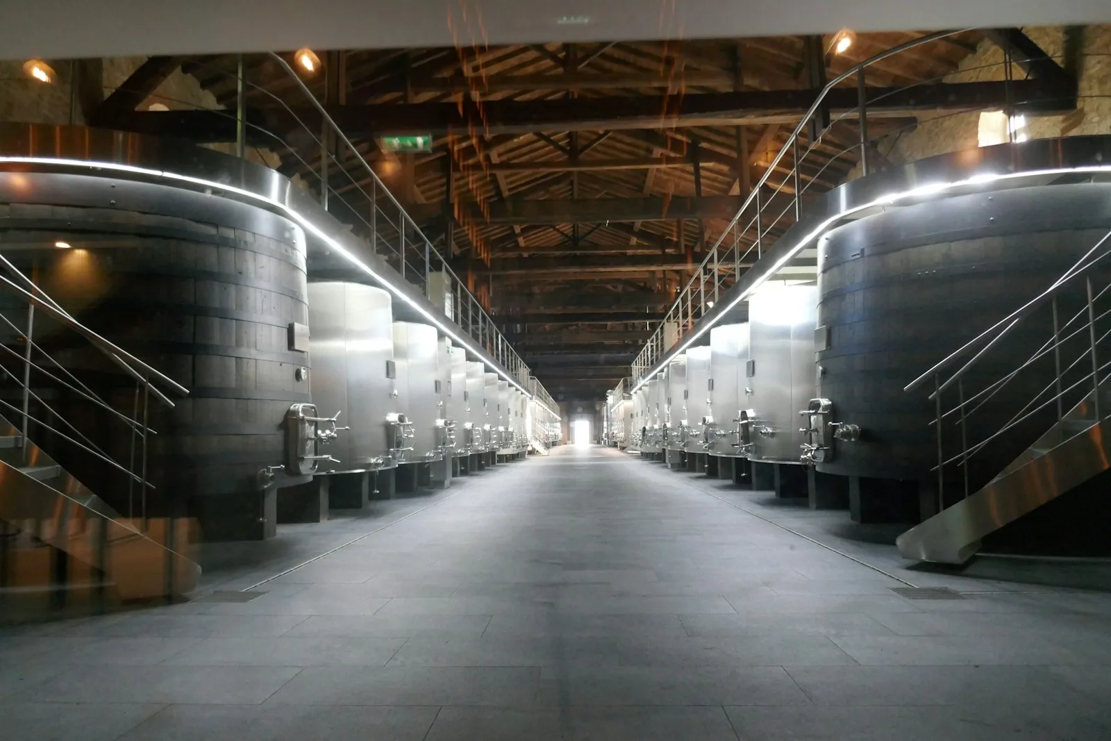 Nave de una bodega con dos filas de grandes depósitos de vino y pasarelas de acceso