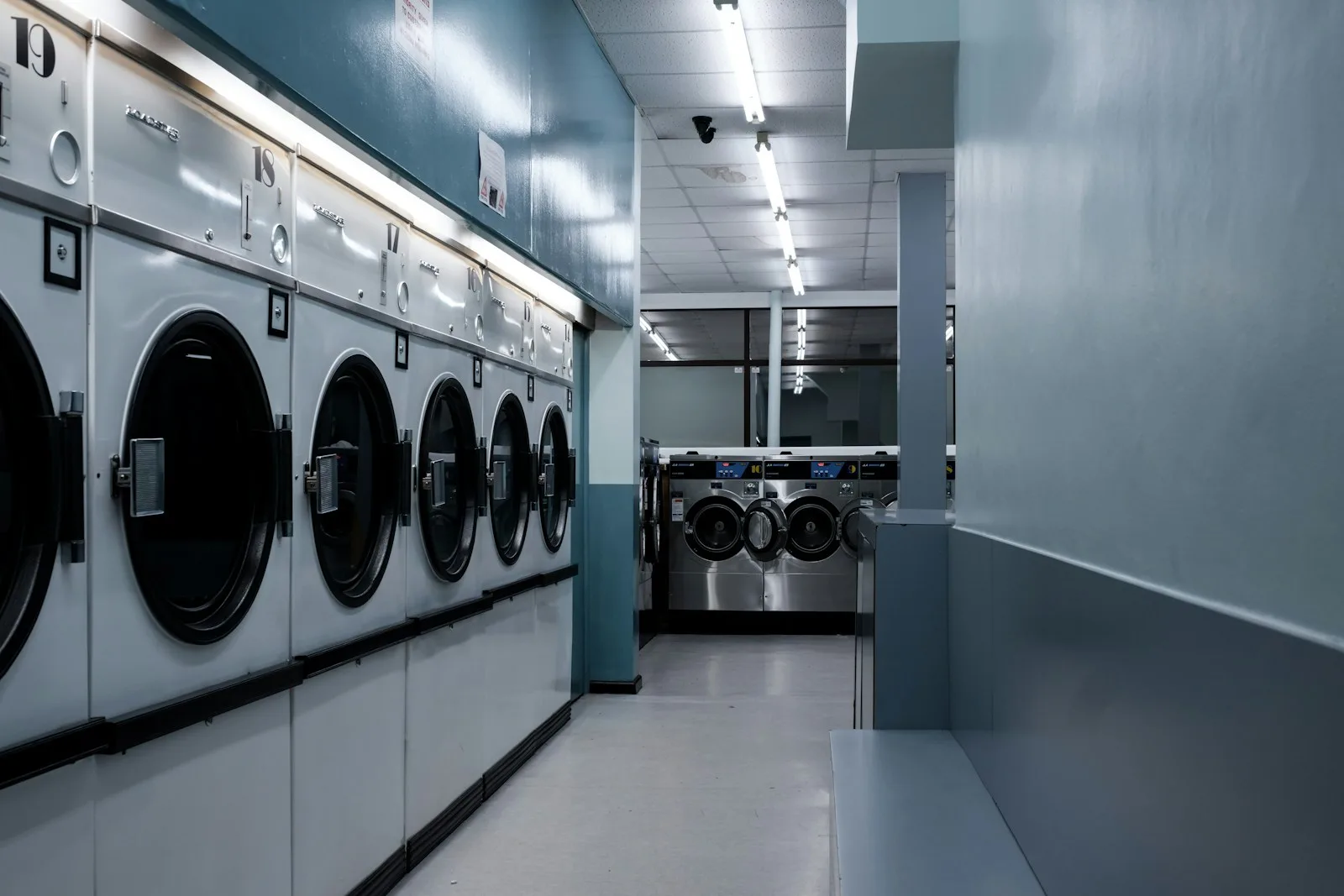 Fila de lavadoras industriales de gran capacidad alineadas en una lavandería profesional