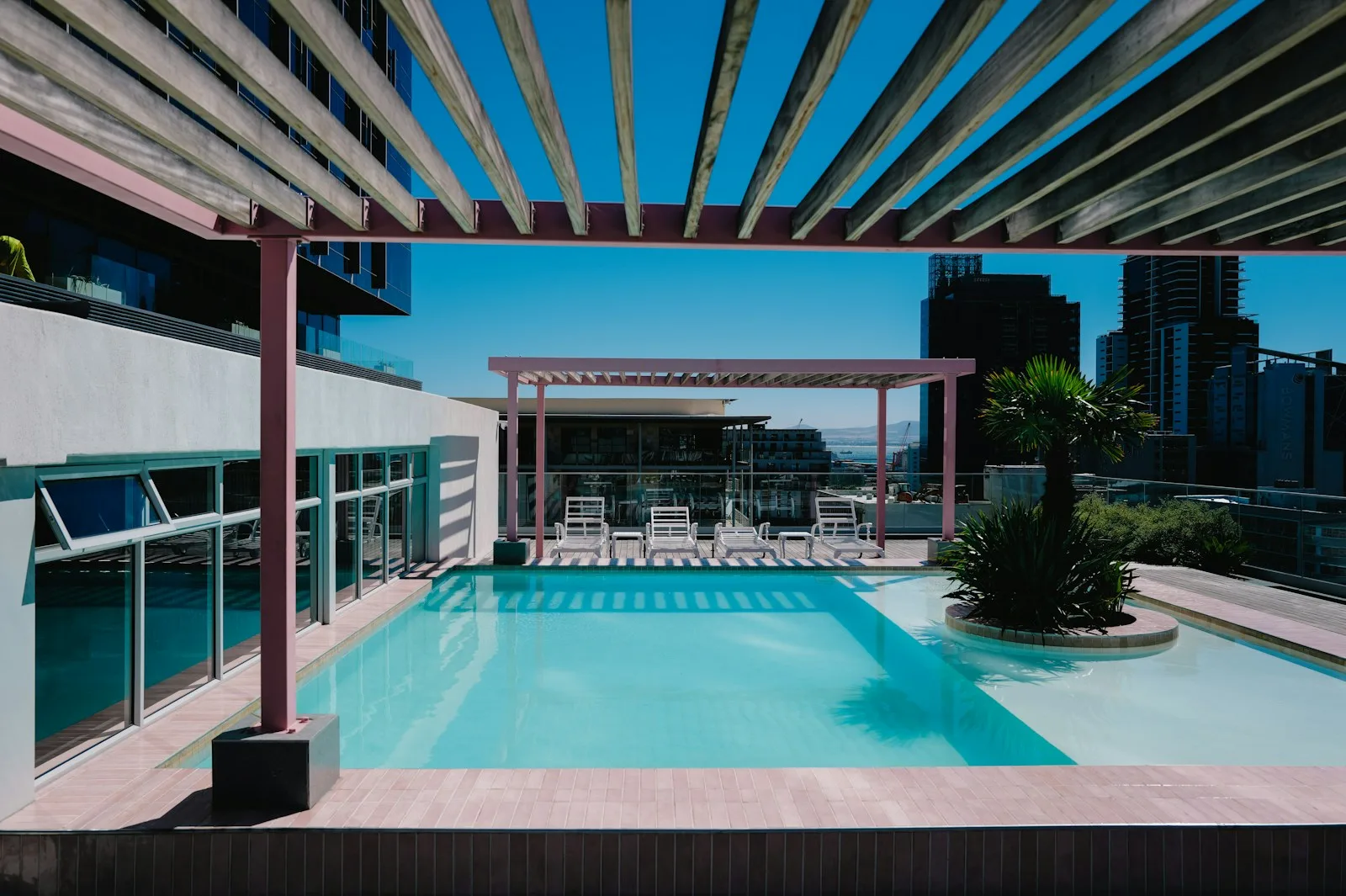 Piscina climatizada en la azotea de un hotel, con tumbonas y pérgola