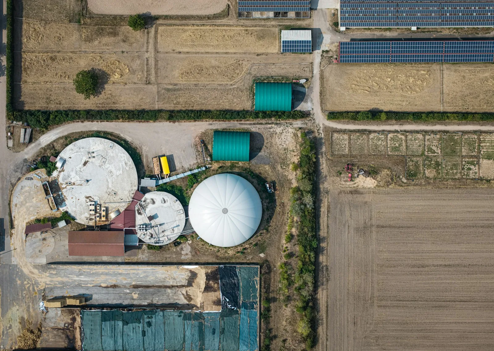 Vista aérea de una planta de biogás con sus digestores circulares junto a campos de cultivo