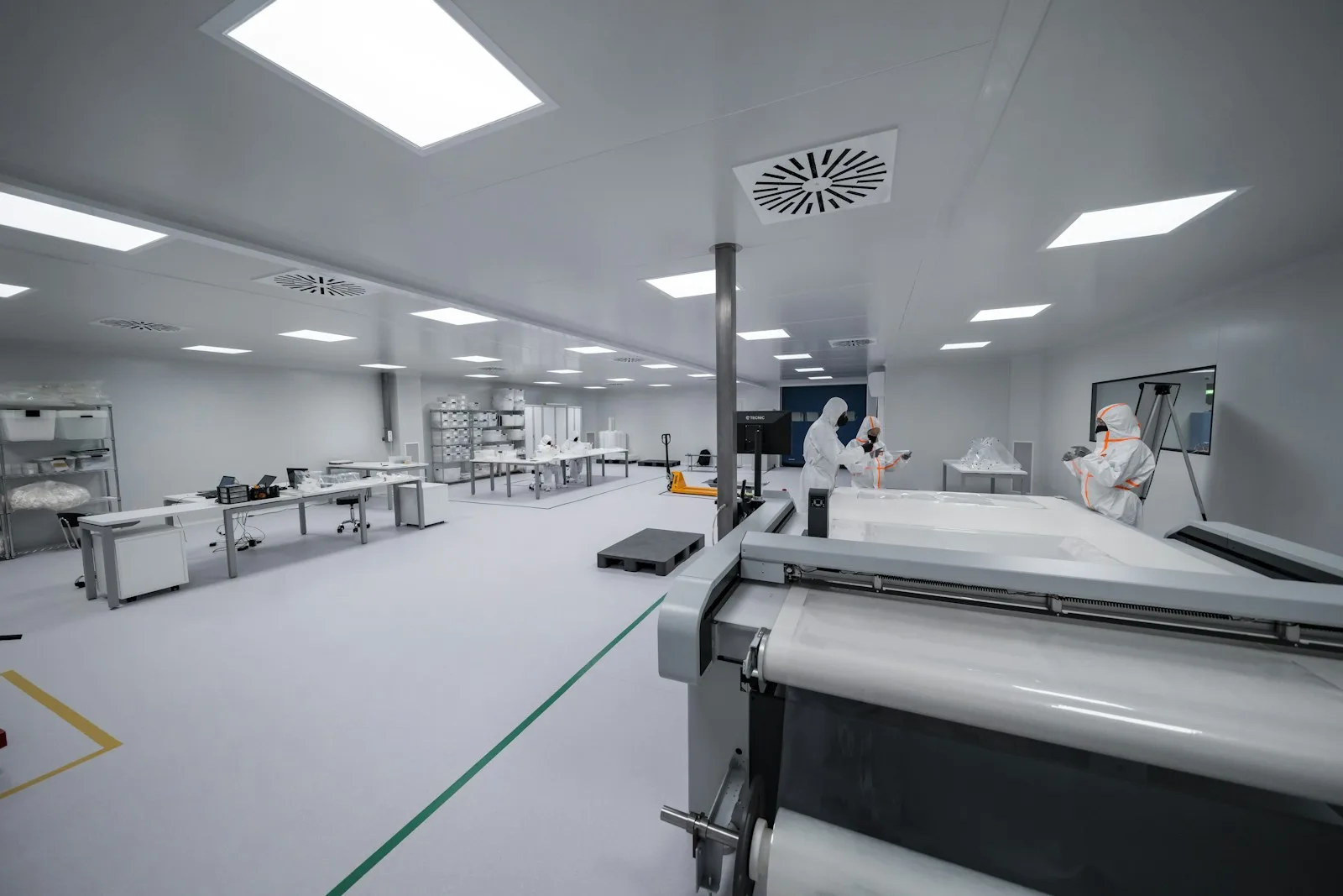 Operarios con equipo de protección trabajando en la sala blanca de una planta farmacéutica